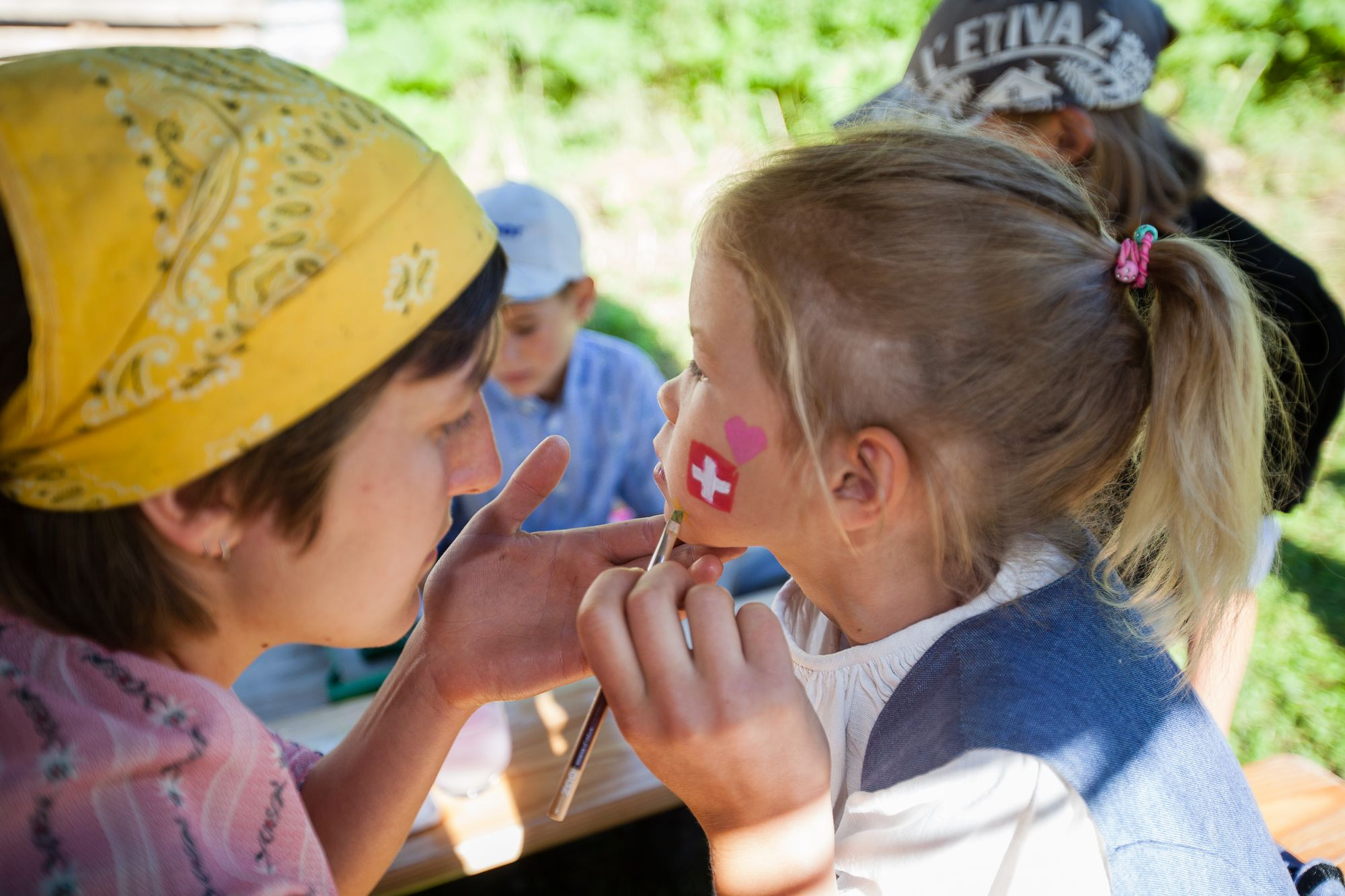 Une bénévole peint le drapeau suisse sur le visage de Alissia